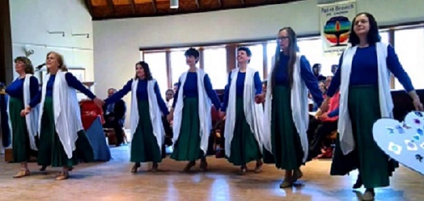 seven dancers in matching attire perform in front of an audience